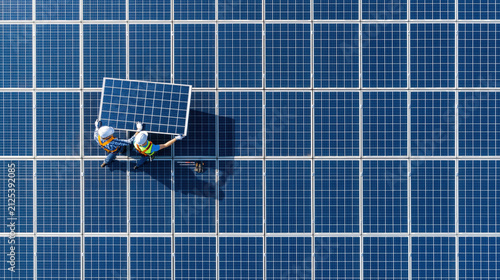 Solar panel technicians installing module on large rooftop array in aerial drone view showing geometric pattern and teamwork