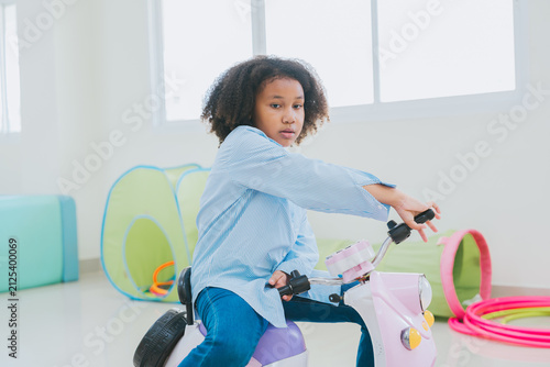 Canvas Print Young girl playing with toy scooter feels focused and engaged while enjoying pla