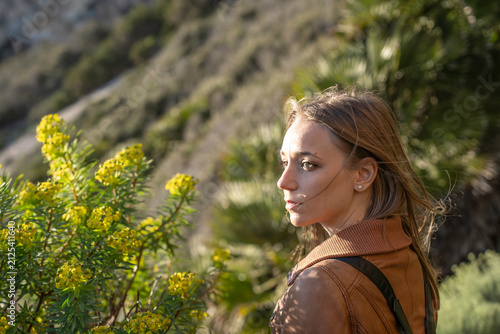 Foto Pensive millennial woman explores a sunlit botanical garden while looking into the distance beside flowering plants