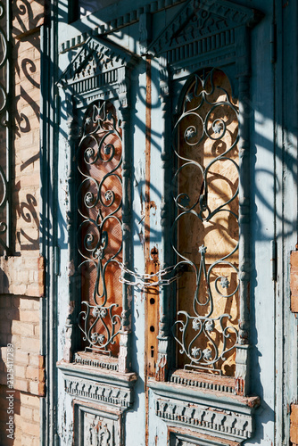Vintage double wooden door with ornate ironwork chained and weathered facade
