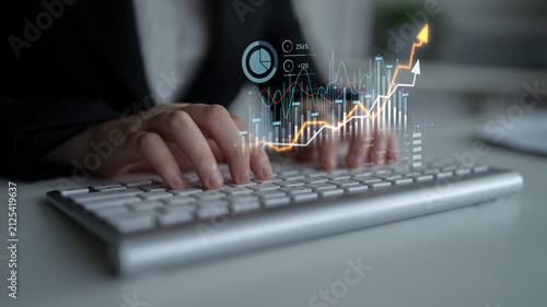 Canvastavla A business professional engages with financial data on a keyboard, surrounded by vibrant graphs and growth indicators displaying dynamic trends in a modern office setting