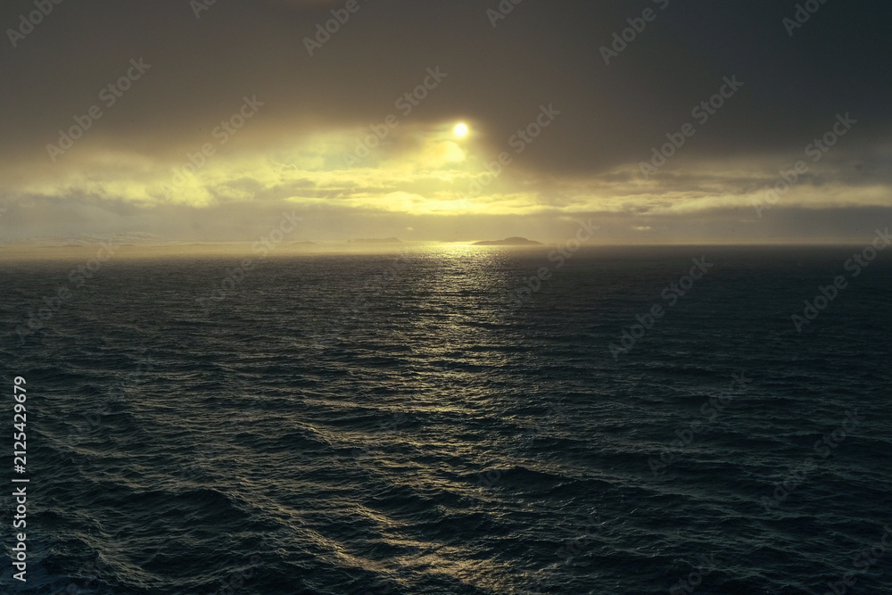 Fototapeta premium Golden sunlight breaking through clouds over the sea