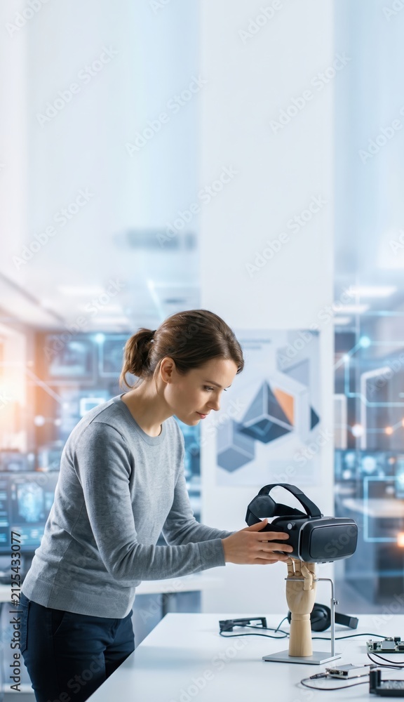 Fototapeta premium Young researcher testing virtual reality headset on robotic hand in modern lab