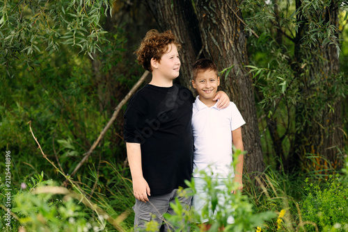 Cuadro en lienzo Portrait of two brothers standing together in park greenery during summer day