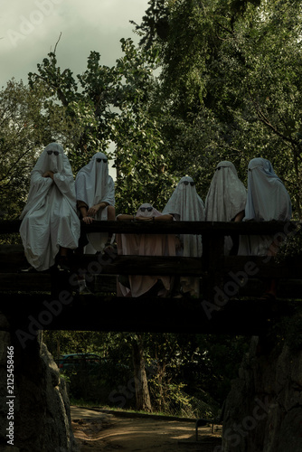 People Dressed as Ghosts Standing on a Wooden Bridge in a Forest
