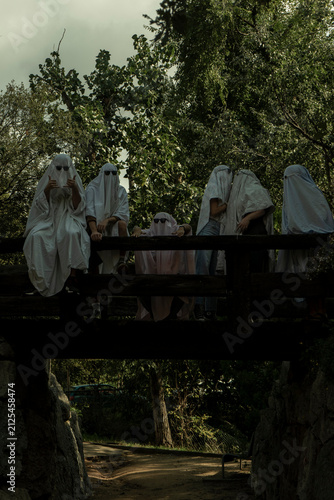 People Dressed as Ghosts Standing on a Wooden Bridge in a Forest