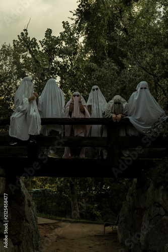 People Dressed as Ghosts Standing on a Wooden Bridge in a Forest