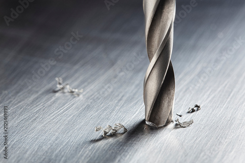 drill bit make hole in metal aluminum plate with small chip. Locksmith work. Industry of construction.