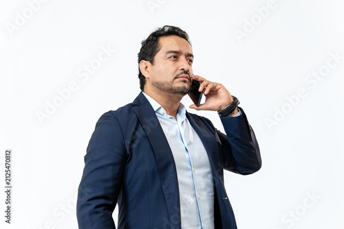 Latino businessman communicating on smartphone against white background