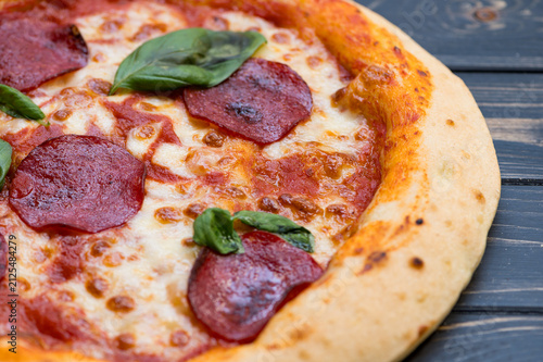 gluten-free pizza shows pepperoni slices and fresh basil on a wooden surface