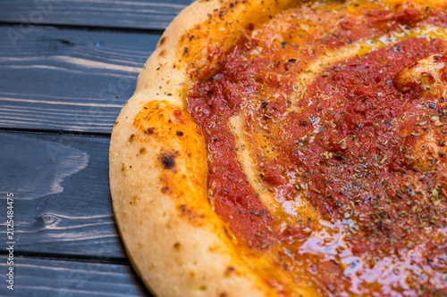 gluten-free pizza with sauce and spices sits on a dark wooden table