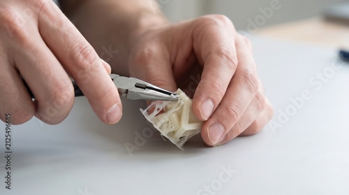 Plakat w ramie Person using pliers to remove support structures from a small 3D printed object