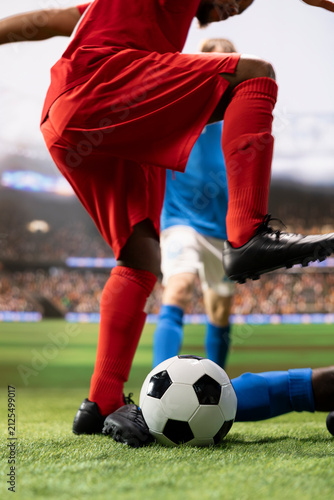 Canvastavla Close-up captures a tackle for ball possession in a dynamic soccer match, with a red team striker dribbling toward the goal net and an opponent stopping the attack inside the penalty box