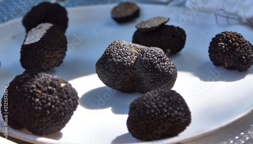 Canvas Print Black truffles arranged on a white plate with a textured surface, showcasing the