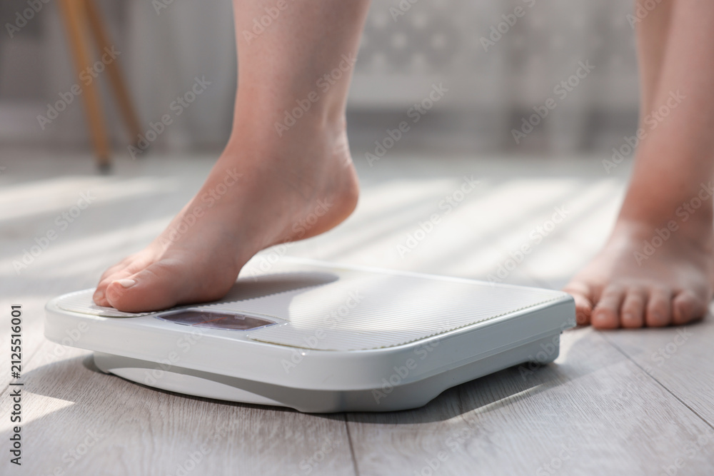 Fototapeta premium Overweight woman on scale at home, closeup