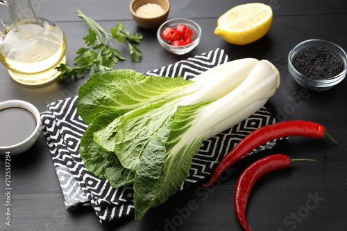 Obraz na plátně Fresh bok choy cabbage and other products on black wooden table, closeup