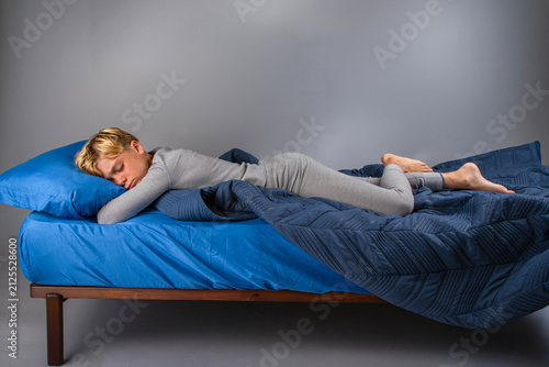 Boy in grey pajamas sleeping peacefully on a bed