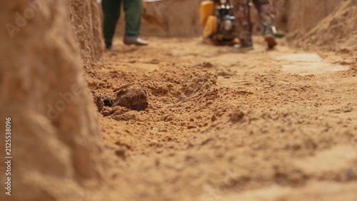 Workers are compacting sand and preparing the foundation for future development at an active construction site, ensuring stability and readiness for building