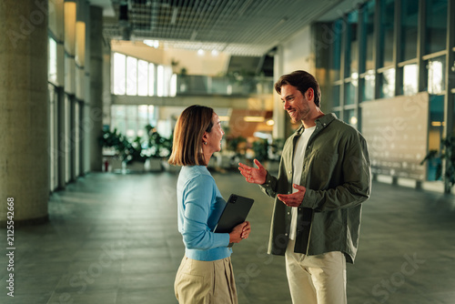 Business colleagues having casual conversation in modern office lobby, discussing work during an informal meeting