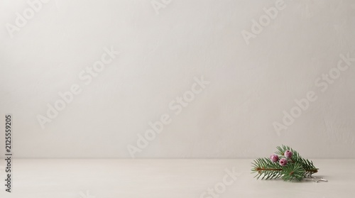 minimalist christmas background with pine branch and red berries on light surface copy space