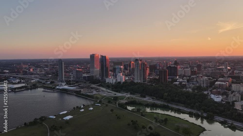 Aerial View of Milwaukee Skyline at Dusk with Lakefront Park and Lagoon” Aerial view of downtown Milwaukee, Wisconsin at dusk, with skyscrapers catching pink sunset light above a lakefront park, lagoo