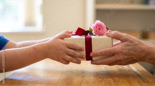 A child's hand giving a beautifully wrapped gift to an elderly person's hand.