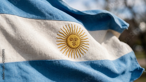 Foto Argentine national flag billowing in the wind with sun emblem against a blurred