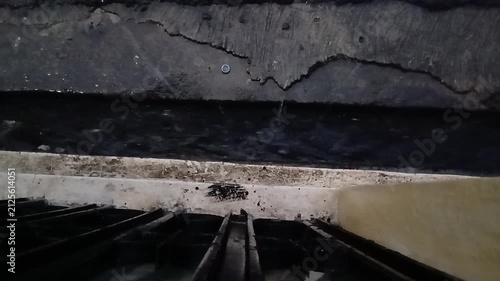 Close up shot of water streaming through a concrete drainage ditch next to a building wall during rain