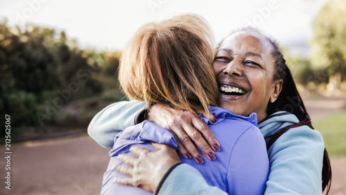 Multiracial senior women hugging each other in public park - Elderly friendship and love concept