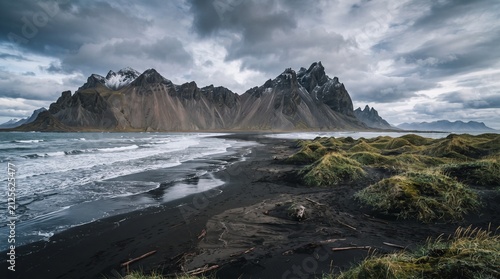 Dramatic Vestrahorn mountain range on a black sand beach in Iceland with stormy clouds and crashing waves representing rugged nature and adventure travel