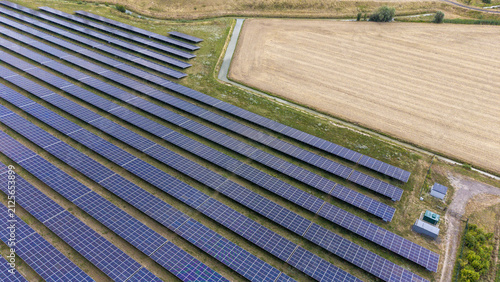 Aerial view of rows of solar panels installed in a rural field with an irrigation ditch and agricultural land in Echteld, Gelderland, Netherlands.