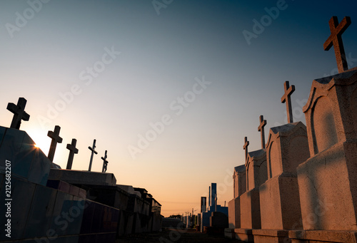 Fotografie Christian cemetery pathway with stone crosses illuminated by sunrise