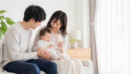 父親と母親が乳児を抱いて見守るリビングの育児風景