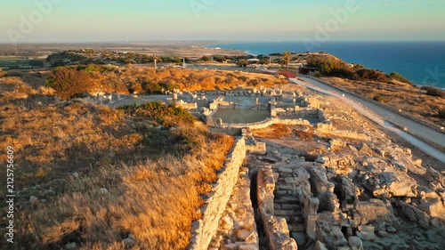 Aerial view of the Archaeological Site of Kourion at golden hour. Ancient remains and the theatre area are bathed in warm sunset light.