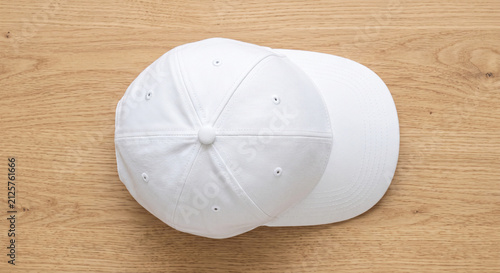 Clean white baseball cap with a classic design on a light wooden background top view with copy space for branding or casual wear concepts