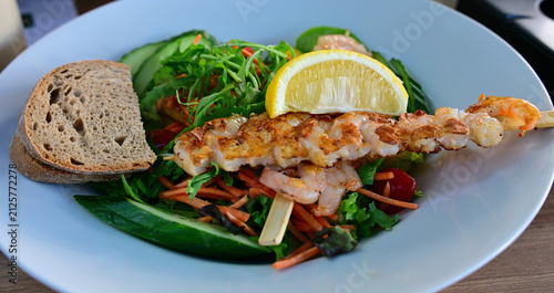 Gemüsesalat und Garnelen Spieße serviert mit der Scheibe Brot und Zitrone