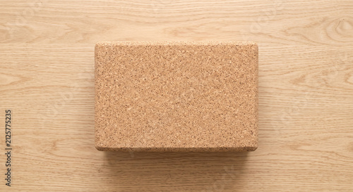 Top view of a single cork yoga block on a light wooden background providing support and stability for various yoga poses and exercises