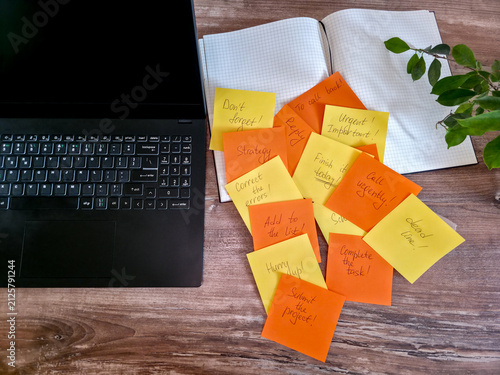 Pile of colorful sticky notes scattered on a desk beside a laptop