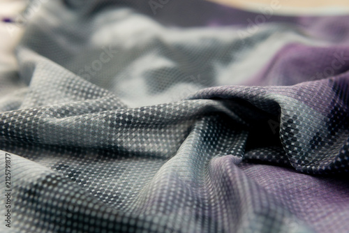 Close-up abstract background texture of wrinkled sportswear fabric featuring a halftone dot pattern in purple, grey, and white gradient tie-dye effect.