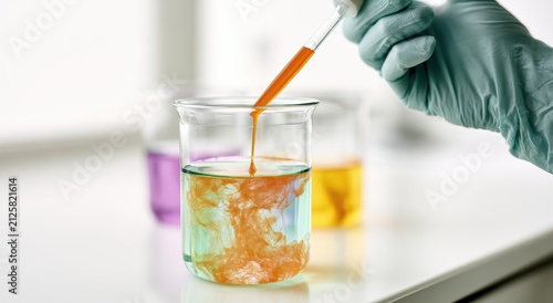 Dropper adding orange liquid to green liquid in a beaker