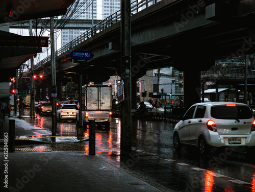 Rainy Bangkok Street Scene with Cars, Elevated Highway and Reflective Wet Pavement