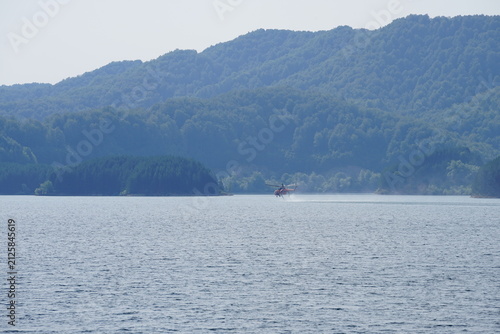 Foto Firefighting Helicopter Approaching Aoos Springs Lake for Water Scooping, Epirus