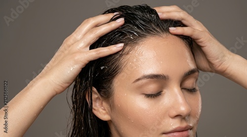 Hair wellness routine featuring the application of a scalp treatment to wet dark hair.