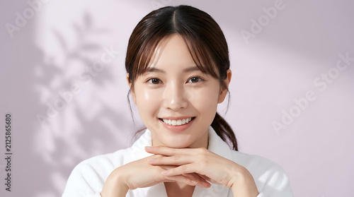 portrait of a smiling young woman with hand under chin in bright studio background emphasizing her joyful expression and natural