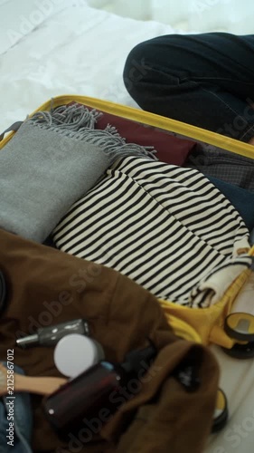 Young woman packing clothes into a suitcase for an upcoming trip at home. Travel preparation, vacation planning. Organized luggage, minimalist packing. Smart travel lifestyle.
