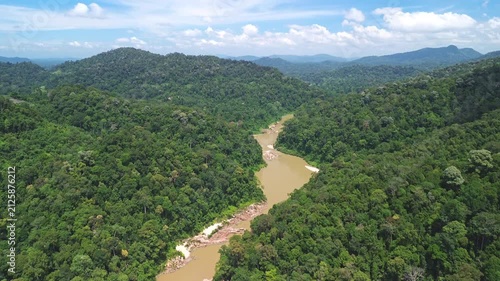 Drone vertical reveal from the Sungai Tembeling to forested hills and blue sky above pristine primary rainforest near Taman Negara, Pahang, Malaysia, May 2026.