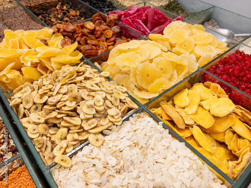 Variety of colorful dried fruits on a store display. Glass bins with mango, pineapple, banana chips, and other dried fruits, symbolizing natural abundance and healthy nutrition