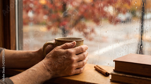 Woman's Hands Wrapped Around Ceramic Mug of Hot Chai at Rainy Autumn Café Window