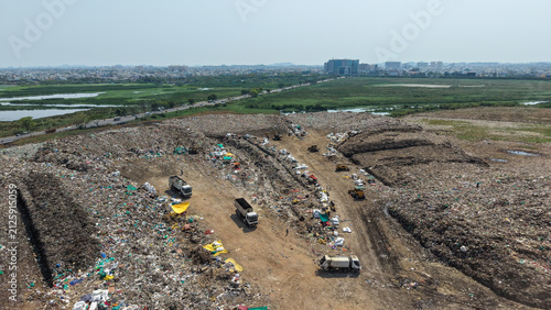 Dump trucks moving waste at an active landfill on the edge of the city