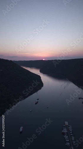 Scenic wide-angle landscape view of Lim Bay (Lim Fjord) at sunset, showing the calm sea channel winding through forested karst hills under a pink and purple twilight sky in Istria, Croatia.
